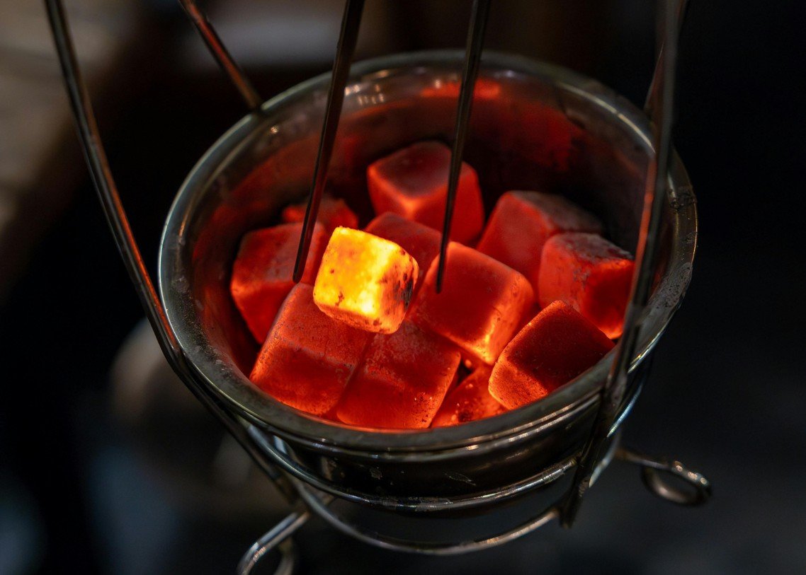 Shisha briquettes glowing in a hookah charcoal basket